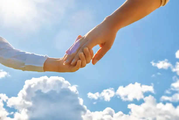 Photo of Hands of adult and child on blue sky background