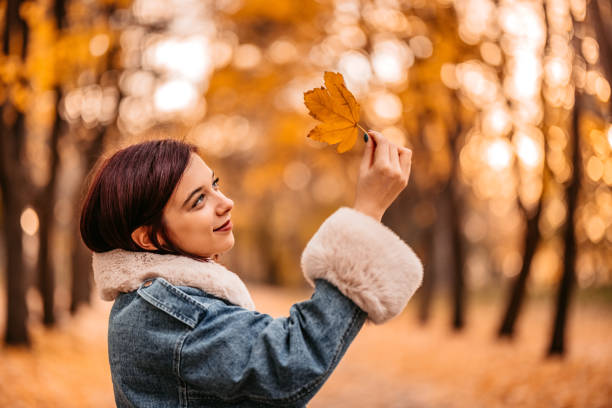 istock Young Woman Holding An Autumn Leaf In Park 1415774524