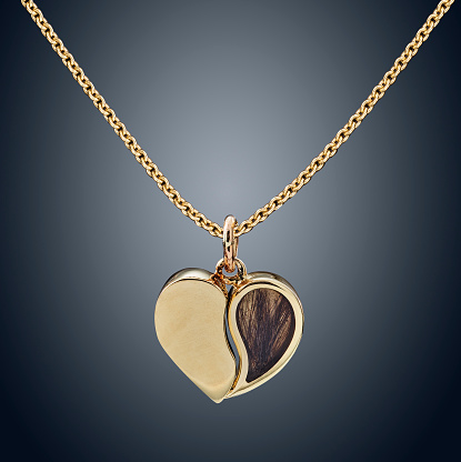 Golden necklace with golden heart isolated on grey.