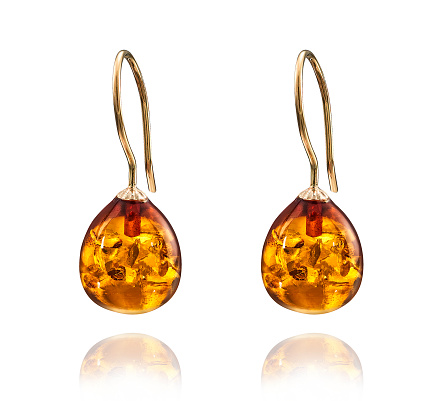 Golden earrings with amber gemstone isolated on white background.