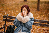 Young Woman Blowing Her Nose In The Park In Autumn