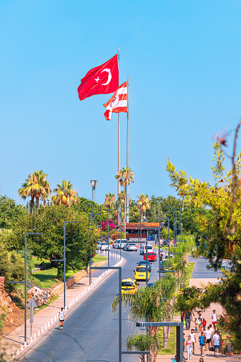 10 July 2022, Antalya, Turkey: City street with automobile road and bicycle and pedestrian path. Turkish flag on an observation point