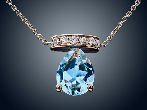 Golden necklace with Aquamarine gemstone isolated on grey