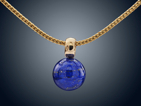 Elegant gold necklace with aquamarine pendant on blue satin background