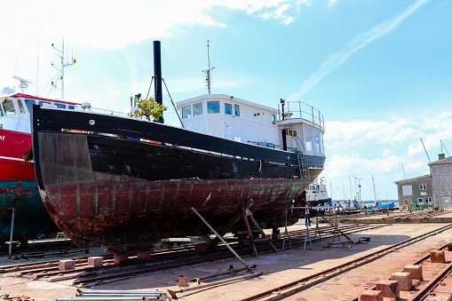 Port of Hundested on a beautiful sunny summer day. Old boat under repair to the shipyard. Small Danish town. Hundested, Denmark - august 11, 2022