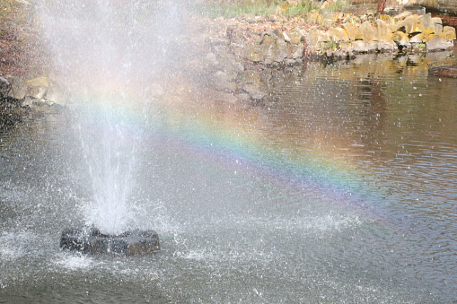 Small fountain in the park. Beautiful rainbow in the sun