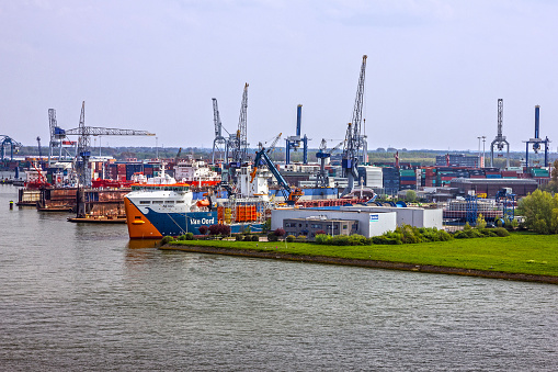 The Harwich Harbour Ferry, with passengers and crew aboard, moored at a pontoon jetty at Shotley Gate in Suffolk, Eastern England. In the distance and to the left are some of the cranes of Port of Felixstowe, Suffolk, and to the right is Harwich in Essex.