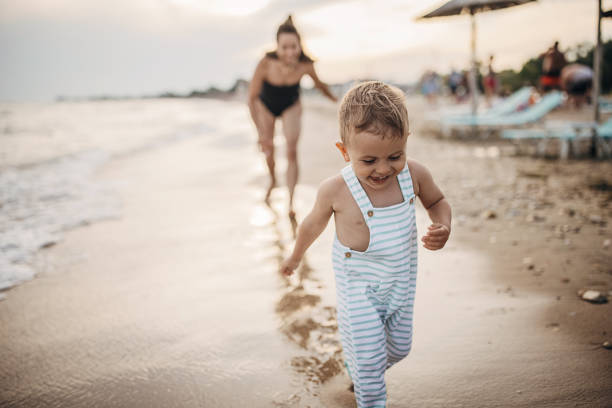 Mother and his little son playing by the sea on the beach, they are on vacation in Greece.
