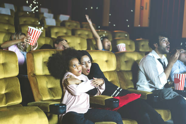 family in the theater see movie. mom has hug daughter and excited. - audience surprise movie theater shock imagens e fotografias de stock