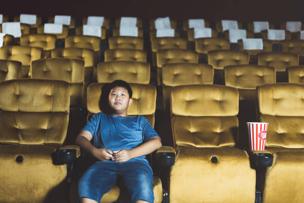 istock Alone asian boy go to cinema with bored feel. 1415788562