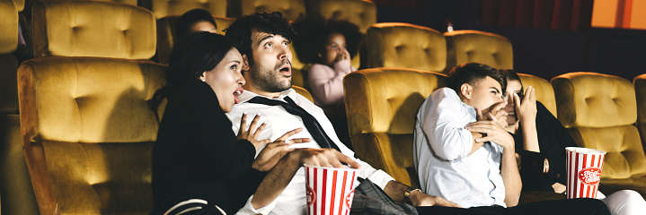Caucasian men with diversity couple watching cinema in theater and surprise expression face. Banner size background with people.