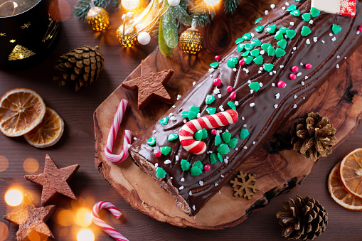 Traditional chocolate trunk cake or log cake on table with Christmas decorations