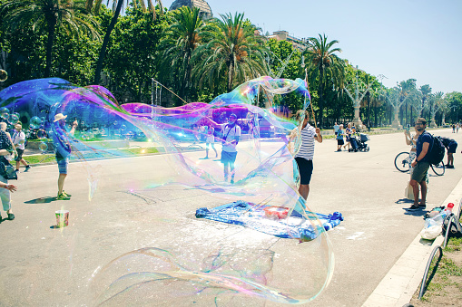 6th June, 2022 - Street performer creating huge bubble art for enthralled passing tourists in the centre of Barcelona, Spain