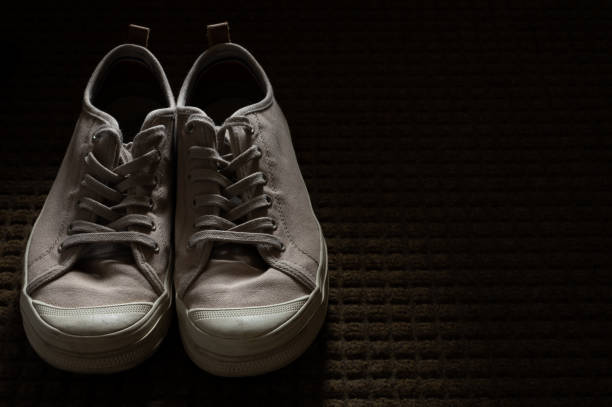 istock Tan Canvas Sneakers on Entry Rug in a Dark Room 1415791904