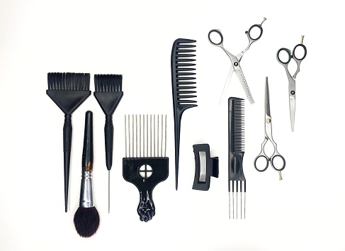 Full frame of professional hair dresser tools on white background. Scissors and comb, brushes. Grooming top view, flat lay black tools.