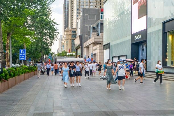 Xi'an, China - July 20, 2022: People walking along a busy boulevard. The boulevard is lined by high-rise offices and trees.