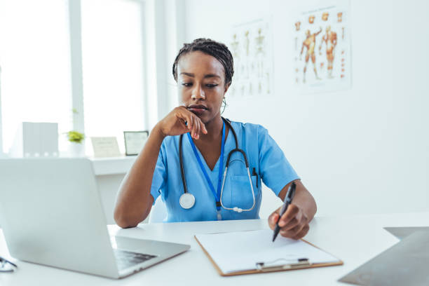 istock Female healthcare worker doing some paperwork and using laptop while working at doctor's office 1415794451