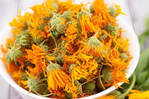 Close-up of a heap of dried calendula flowers on blurred background. Pot marigold is medicinal herbs. Calendula officinalis for infusion or cosmetic products. Top view