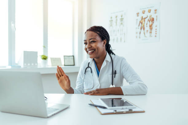 istock Smiling female doctor speaks with patient using laptop online 1415794618