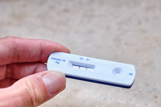 istock Male hand holding a positive COVID-19 rapid antigen test 1415794702
