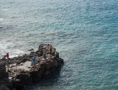 Sardina del Norte, Grand Canaria, Canary islands, Spain, December 13, 2020: Group of angler fishermen fishing at the cllifs in warm winter day.
