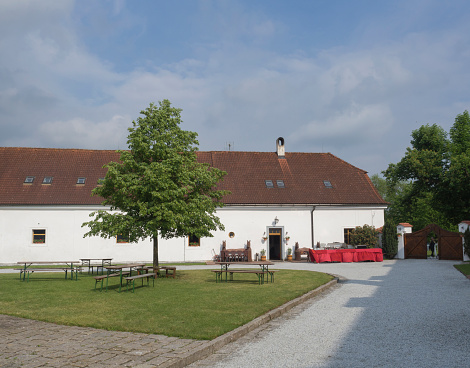 Czech republic, Benice; May 18, 2018: old baroque renovated homestead farm in Benice, building with empty court with buffet tables, green grass, tree and benches