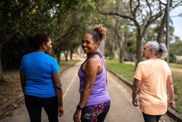 портрет пожилой женщины, прогуливающейся по парку с друзьями - walking exercising relaxation exercise group of people стоковые фото и изображения