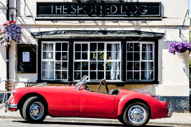 Red Open Top Classic Sports Car Parked Outside A Tradition English Pub Dorking, Surrey Hills, London UK, July 07 2022, Red Open Top Classic Sports Car Parked Outside A Tradition English Pub surrey hotel southeast england england stock pictures, royalty-free photos & images