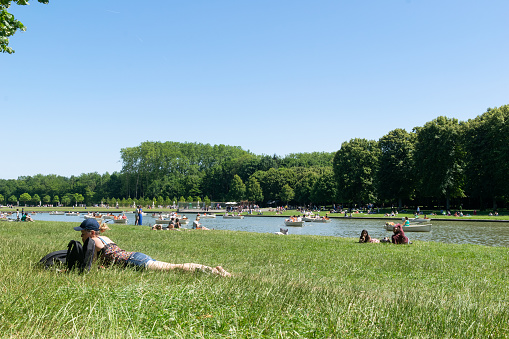 People taking rest in a hot spring day during a heatwave in June 2022, at the gardens of the Versalles Palace, París, France
