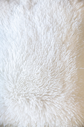 White delicate soft  background of plush fabric. Texture of beige soft fleecy blanket textile with twisted folds.