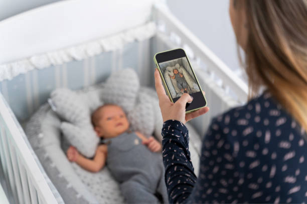 junge mutter, die ein foto von ihrem neugeborenen baby in der wiege macht - phone cradle stock-fotos und bilder