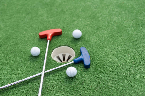 Assorted miniature golf putters and balls askew on synthetic grass. stock photo