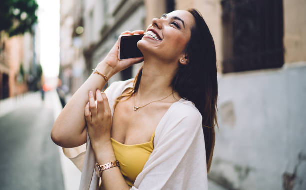 istock Happy Caucaisan tourist laughing during friendly cellphone conversation in roaming, cheerful hipster girl rejoicing while making positive international call communication via smartphone application 1415803068