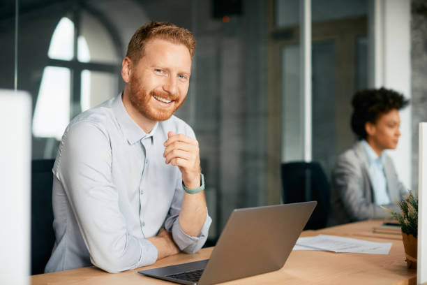 istock Happy businessman working on laptop and looking at camera. 1415806025