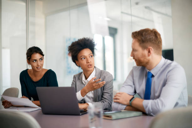 istock Black CEO using laptop while talking to her colleagues during business meeting in the office. 1415806854