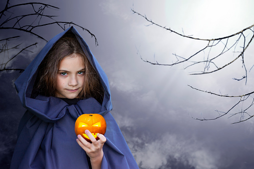 girl with a pumpkin in her hands in the light of the moon outdoors