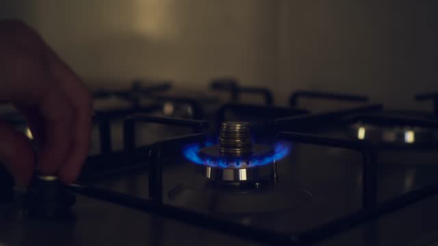 Flame of kitchen burner on stove with stack of coins and blue gas fire turned off due to termination supplies