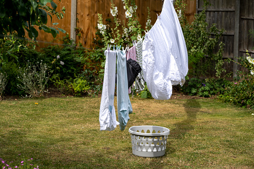 Laundry hung out to dry on a washing line in the back garden of a suburban English house.