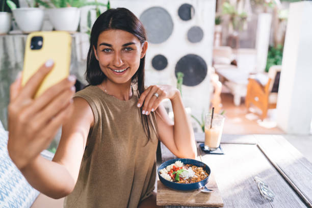 istock Smiling woman taking selfie during breakfast in cafe 1415811993
