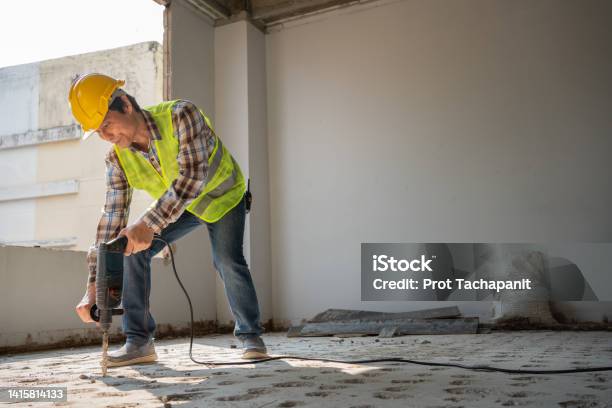 Construction Worker Using An Electric Jackhammer To Drill Perforator Equipment Making Holes Before Pouring The Floor To Be Strong At Construction Site Concept Of Worker And Residential Building Stock Photo - Download Image Now