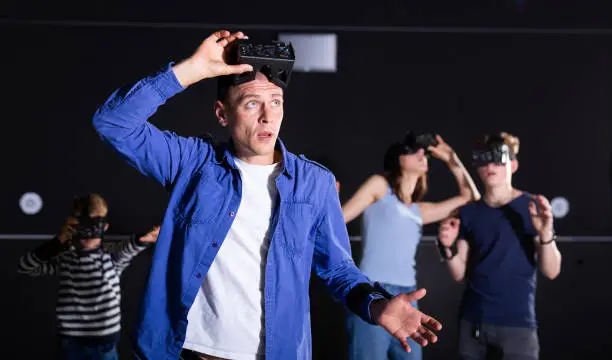 Photo of Young man in VR goggles experiencing virtual reality