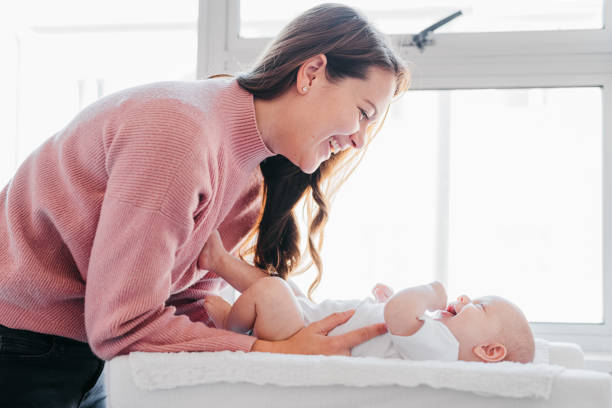 istock Young mother smiling at baby lying down on changing table 1415819011