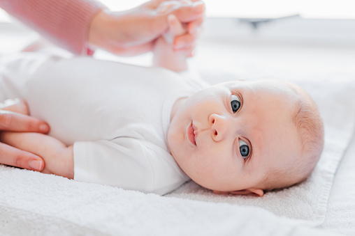 Close-up of adorable and curious baby lying down on changing table, looking into distance