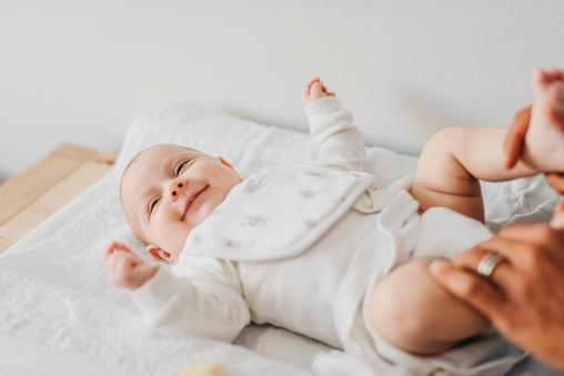 High angle view of smiling baby lying down on changing table