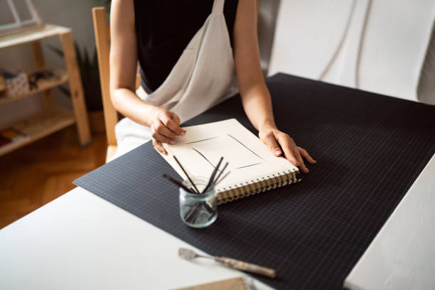 An anonymous woman drawing with charcoal in her studio.