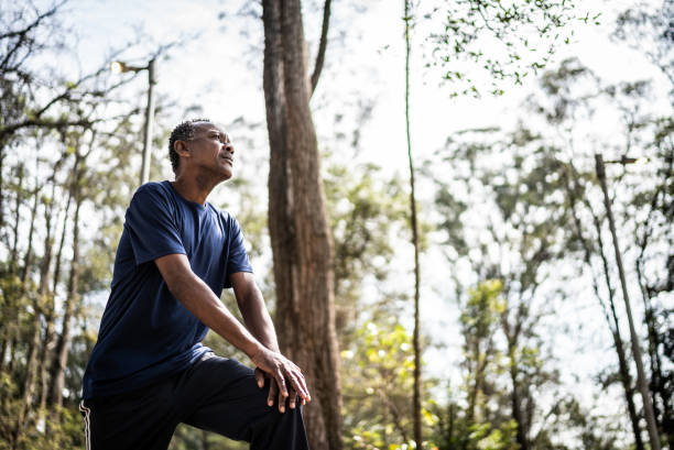starszy mężczyzna relaksujący się, odwracając wzrok po ćwiczeniach w parku - breathing exercise jogging exercising relaxation exercise zdjęcia i obrazy z banku zdjęć