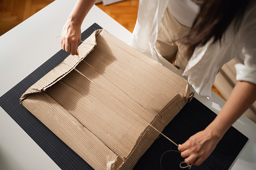 Unrecognizable woman, an artist and online seller, packaging a painting for shipping.