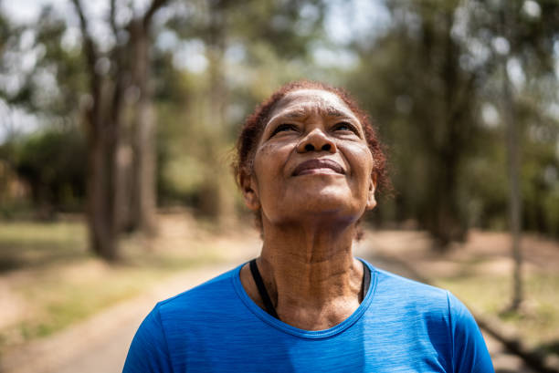 femme âgée contemplative regardant dans un parc - exercising motivation looking up african descent photos et images de collection