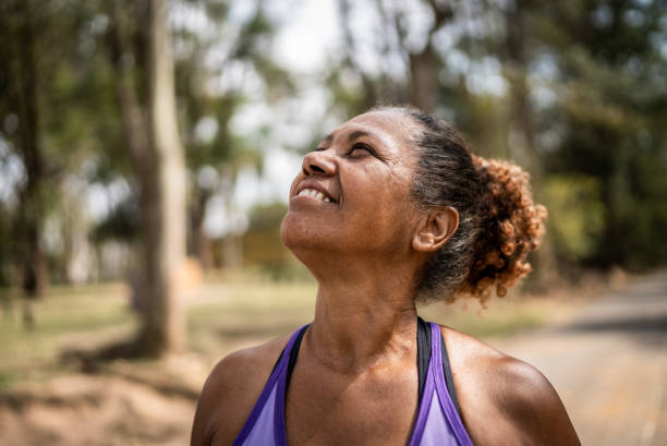 femme âgée contemplative regardant dans un parc - exercising motivation looking up african descent photos et images de collection