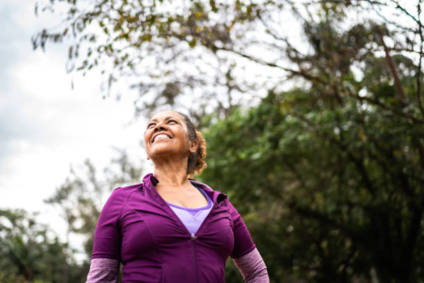 femme âgée contemplative regardant dans un parc - exercising motivation looking up african descent photos et images de collection